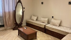Un dormitorio con un espejo grande, un aparador de madera, un sofá con cojines estampados y un suelo con motivo de espiga.
