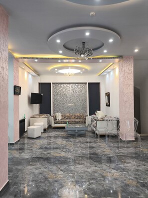 A modern living room with a marble floor, a sofa set, a coffee table, and clear chairs. - hotel janet (Annaba)