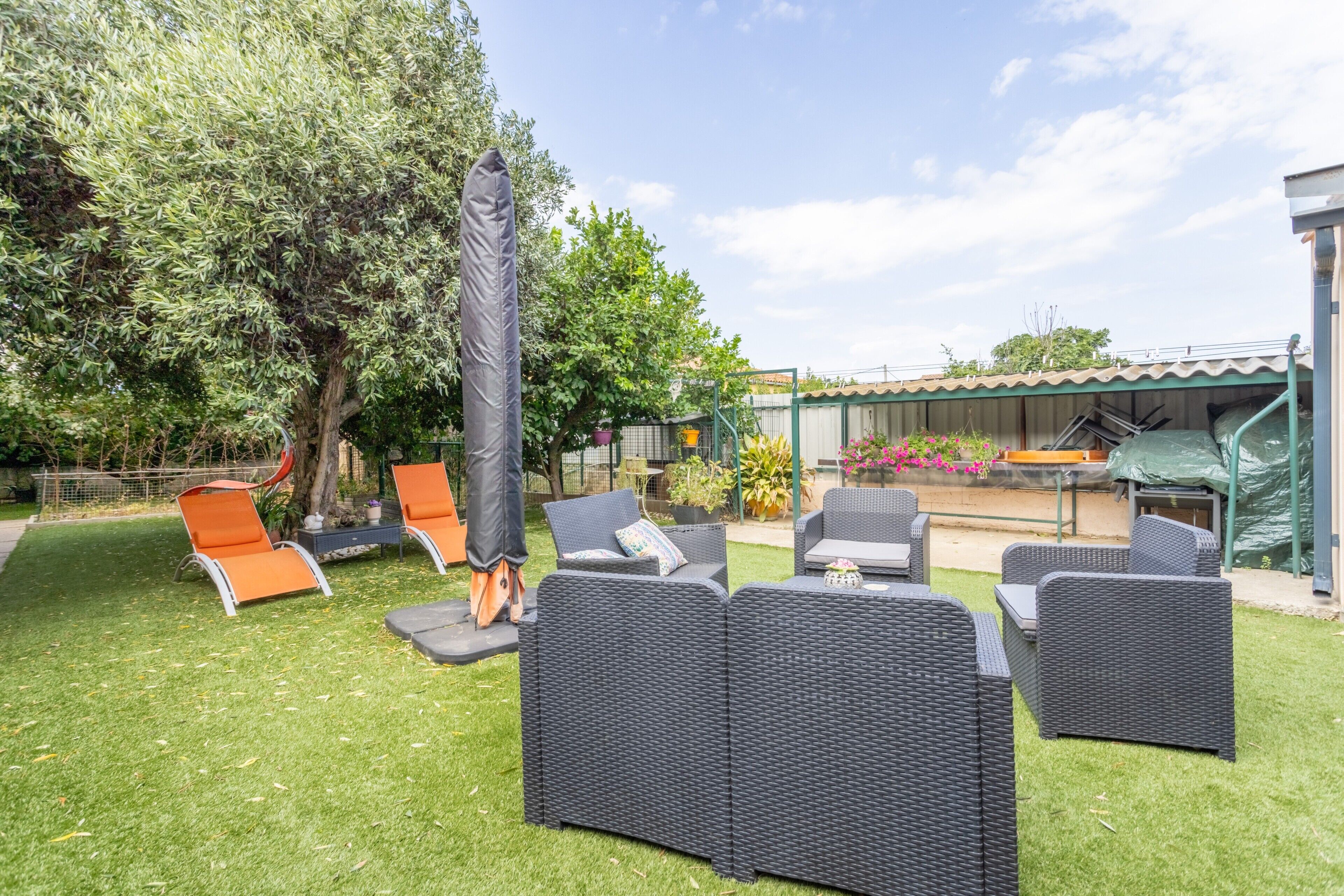 A patio area with outdoor furniture, a tree, and a covered seating area.