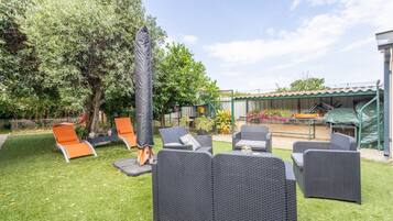 A patio area with outdoor furniture, a tree, and a covered seating area.