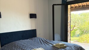 A bedroom with a bed, a wall-mounted TV, and a sliding glass door leading to a balcony.