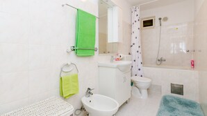 Un baño con lavamanos, inodoro, ducha y espejo.