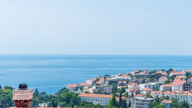 Un pueblo costero con edificios, cielo despejado y el mar al fondo.