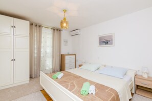 Ein Schlafzimmer mit Bett, Nachttisch, Kleiderschrank, Schreibtisch und einem Fenster mit Vorhängen.