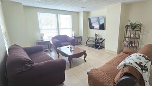 A living room with a couch, a coffee table, a TV, and a bookshelf.
