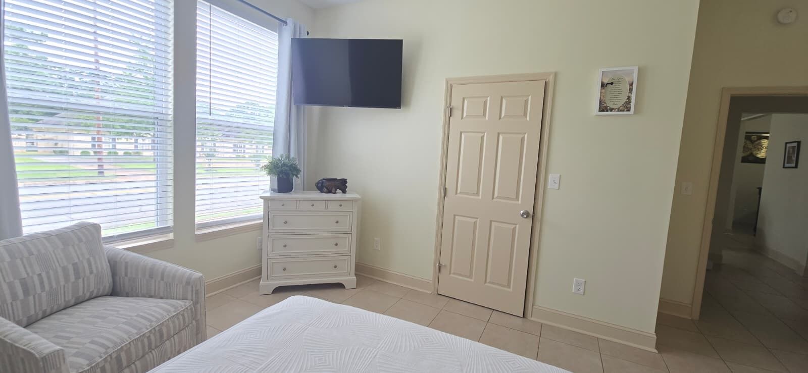 Une chambre à coucher avec un lit, une commode, un téléviseur et une porte.