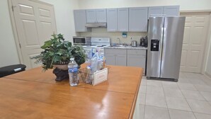 A kitchen with grey cabinets, a stainless steel refrigerator, a microwave, and a stove.