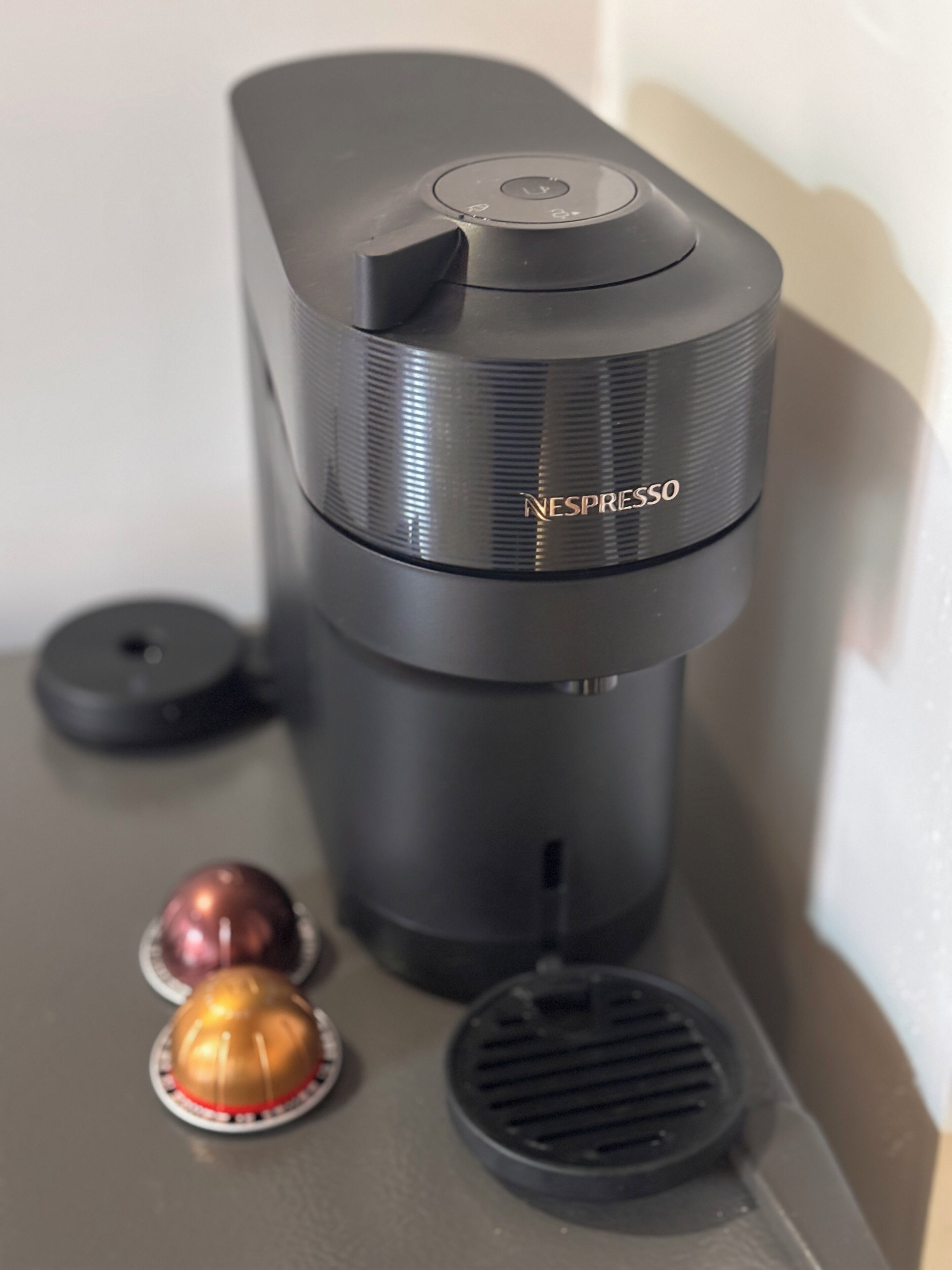 Una máquina de café Nespresso con dos cápsulas y un recipiente para recoger las gotas.