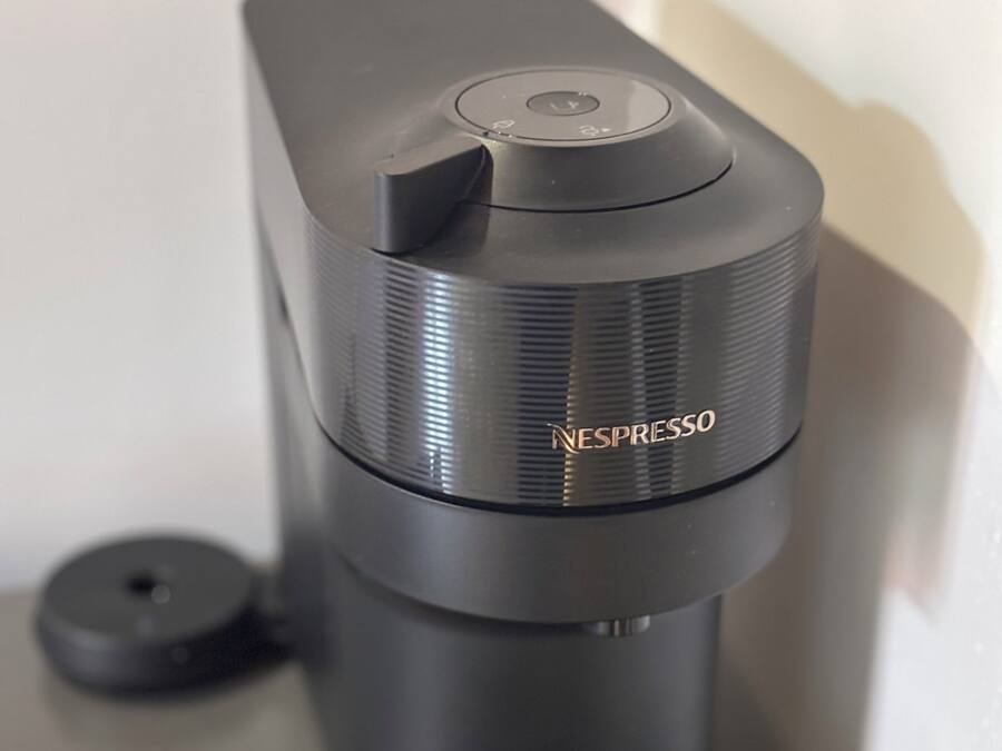Una máquina de café Nespresso con dos cápsulas y un recipiente para recoger las gotas.
