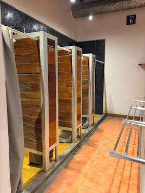 A row of wooden toilet stalls with metal frames and a tiled floor. - Casa Regina CDMX (Mexico City)