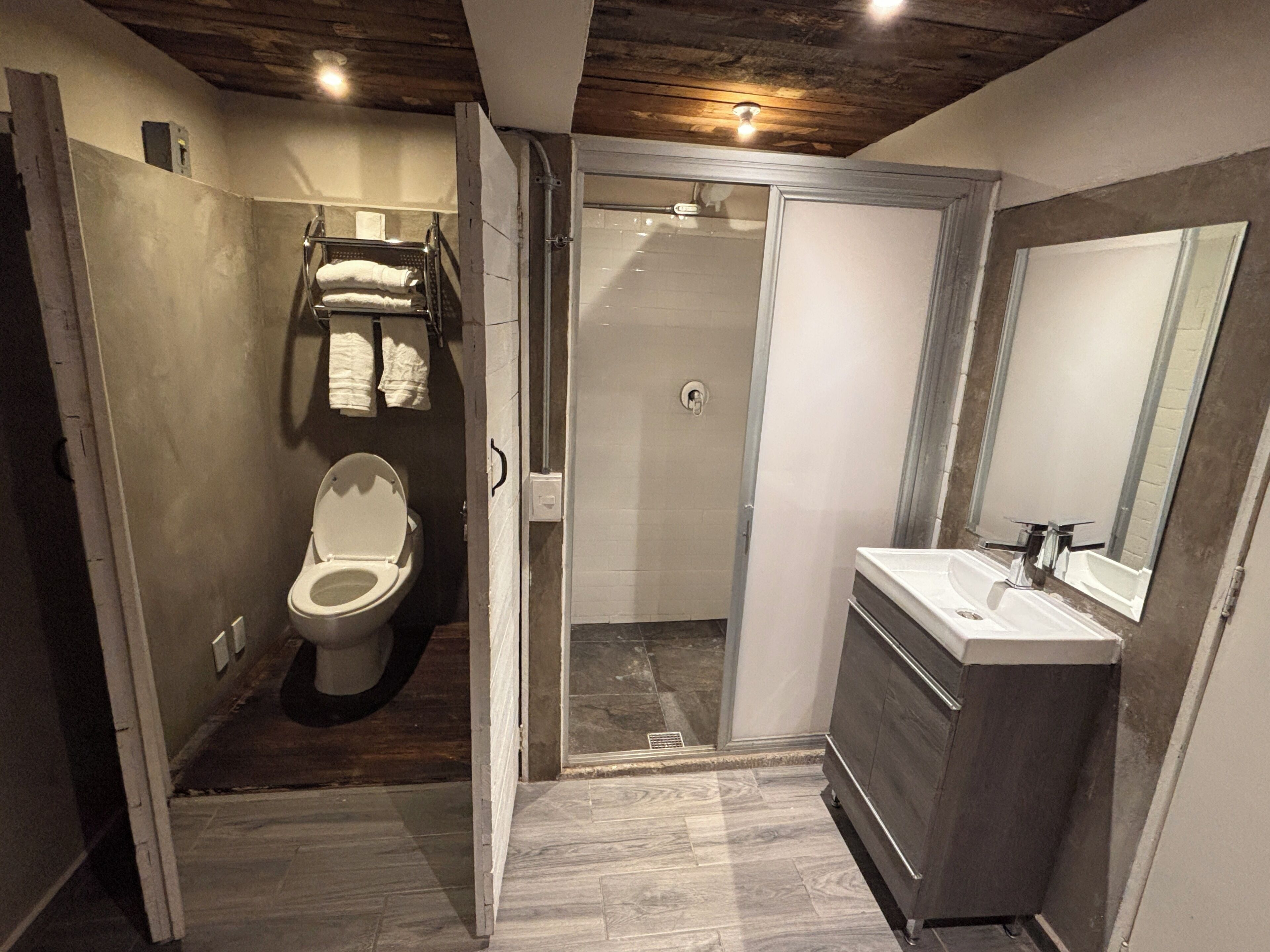 A compact bathroom with a toilet, shower, and sink.