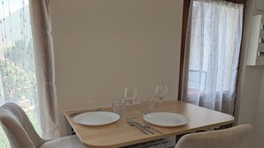 A dining table with two chairs, a plate, a fork, a spoon, and two wine glasses.