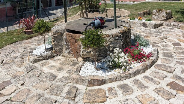 A courtyard with stone paving, a metal structure, and a building with a sloped roof.