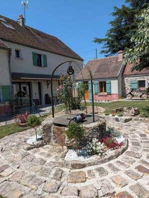 A courtyard with stone paving, a metal structure, and a building with a sloped roof.