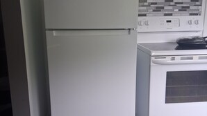 Eine Küche mit einem weißen Kühlschrank, einem Herd und einer gefliesten Spritzwand.