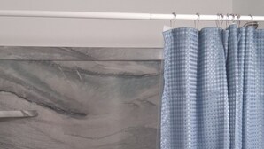 Ein Badezimmer mit einer Badewanne, einer Duschvorhang und einer Marmorwand.