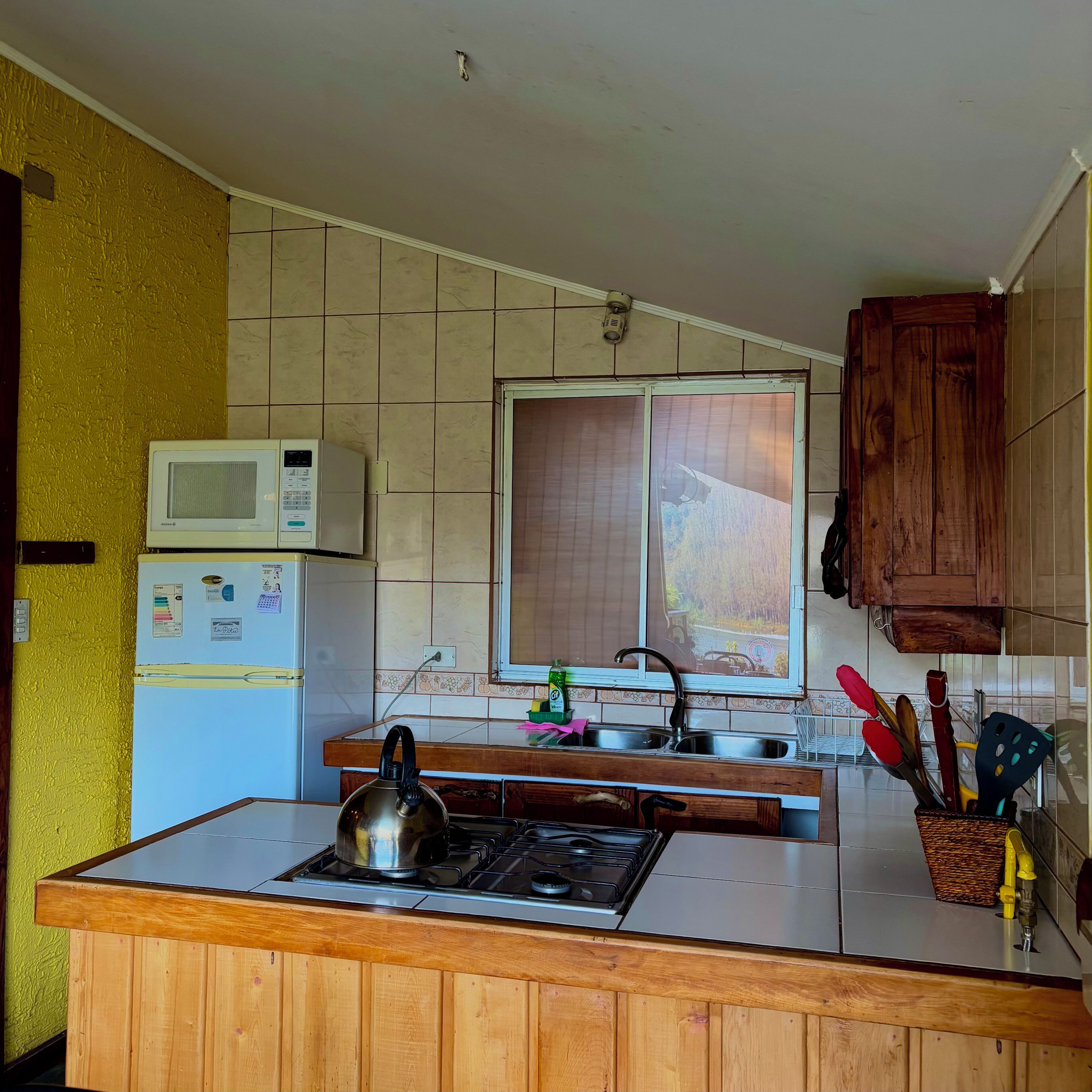 A kitchen with a microwave, refrigerator, stove, and wooden cabinets.
