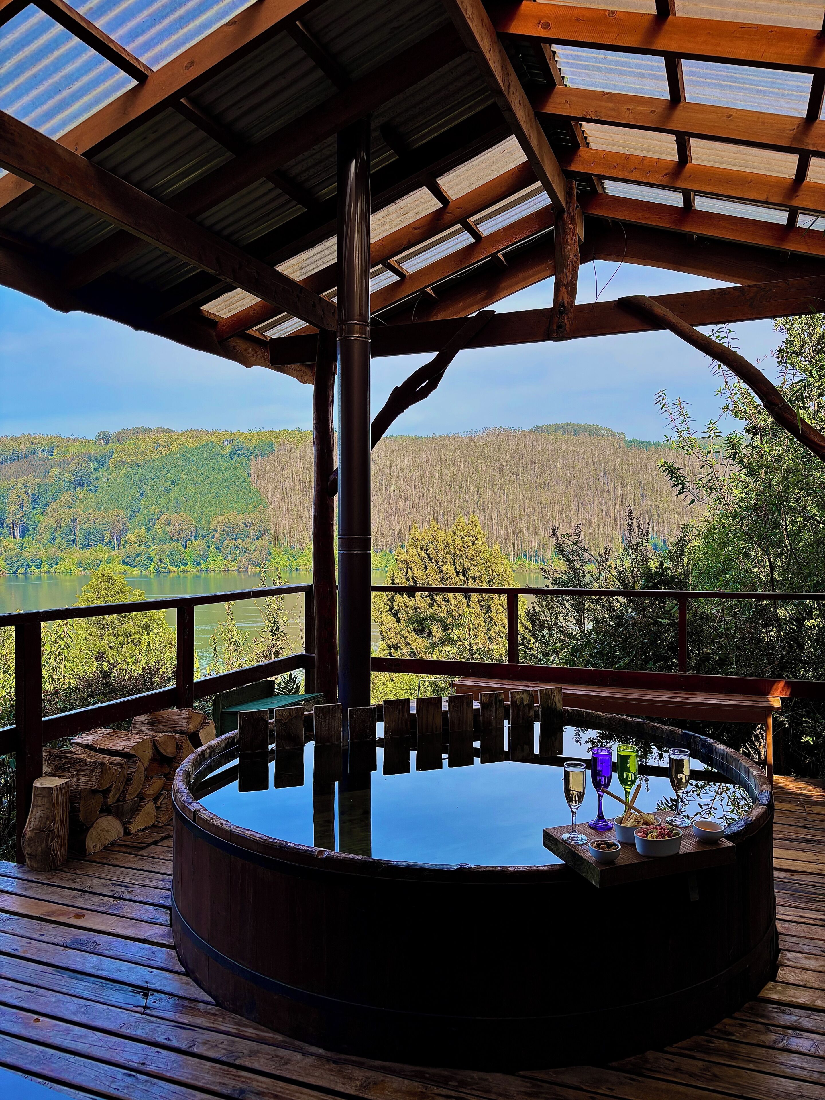 Un jacuzzi con terraza de madera y vistas a un paisaje boscoso.