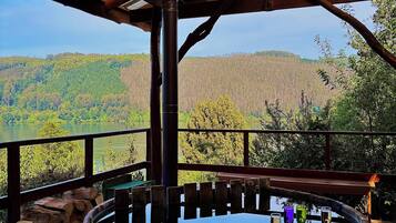 A hot tub with a wooden deck and a view of a forested landscape.