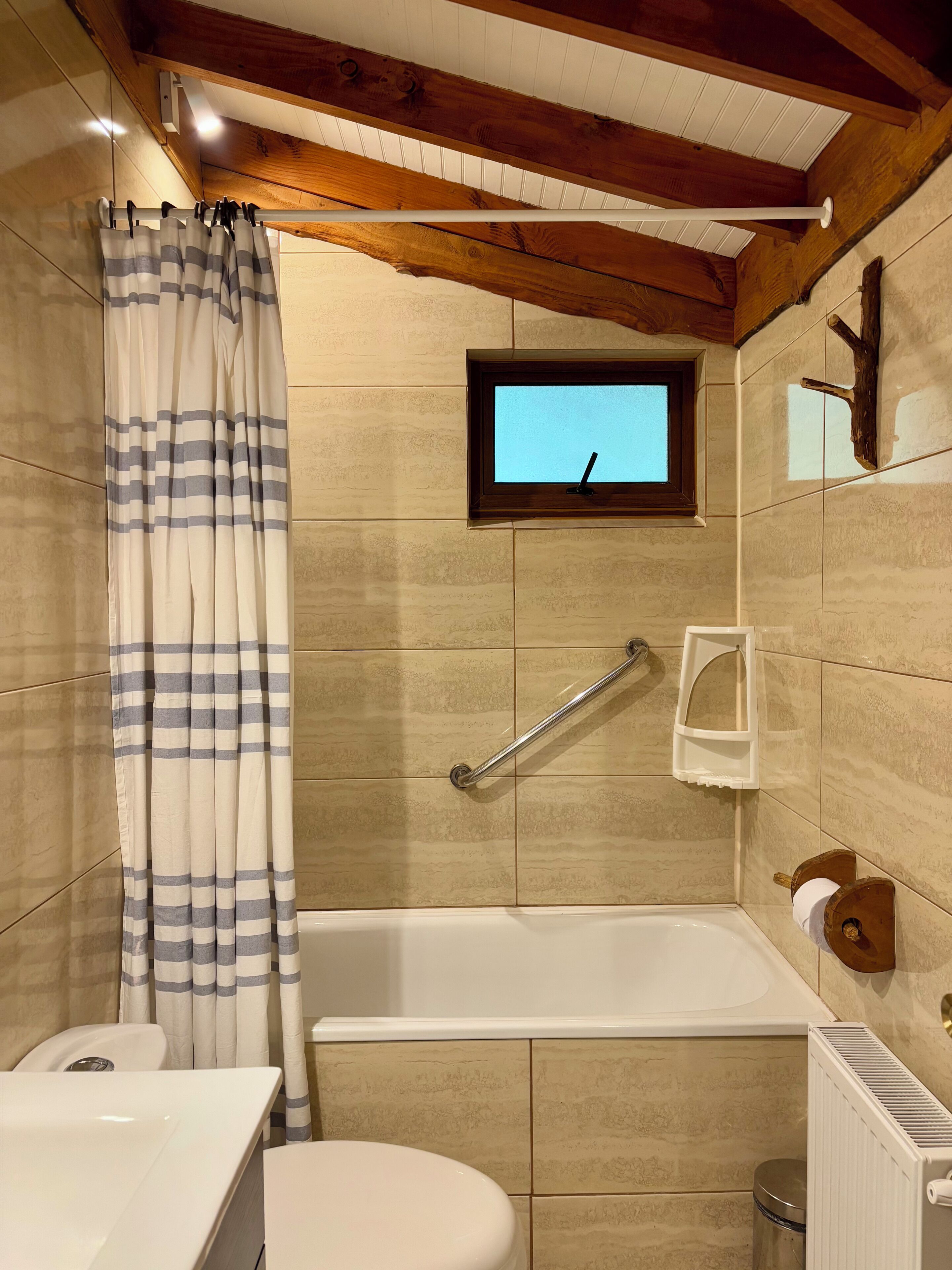 A bathroom with a bathtub, a window, a towel rack, and a toilet.
