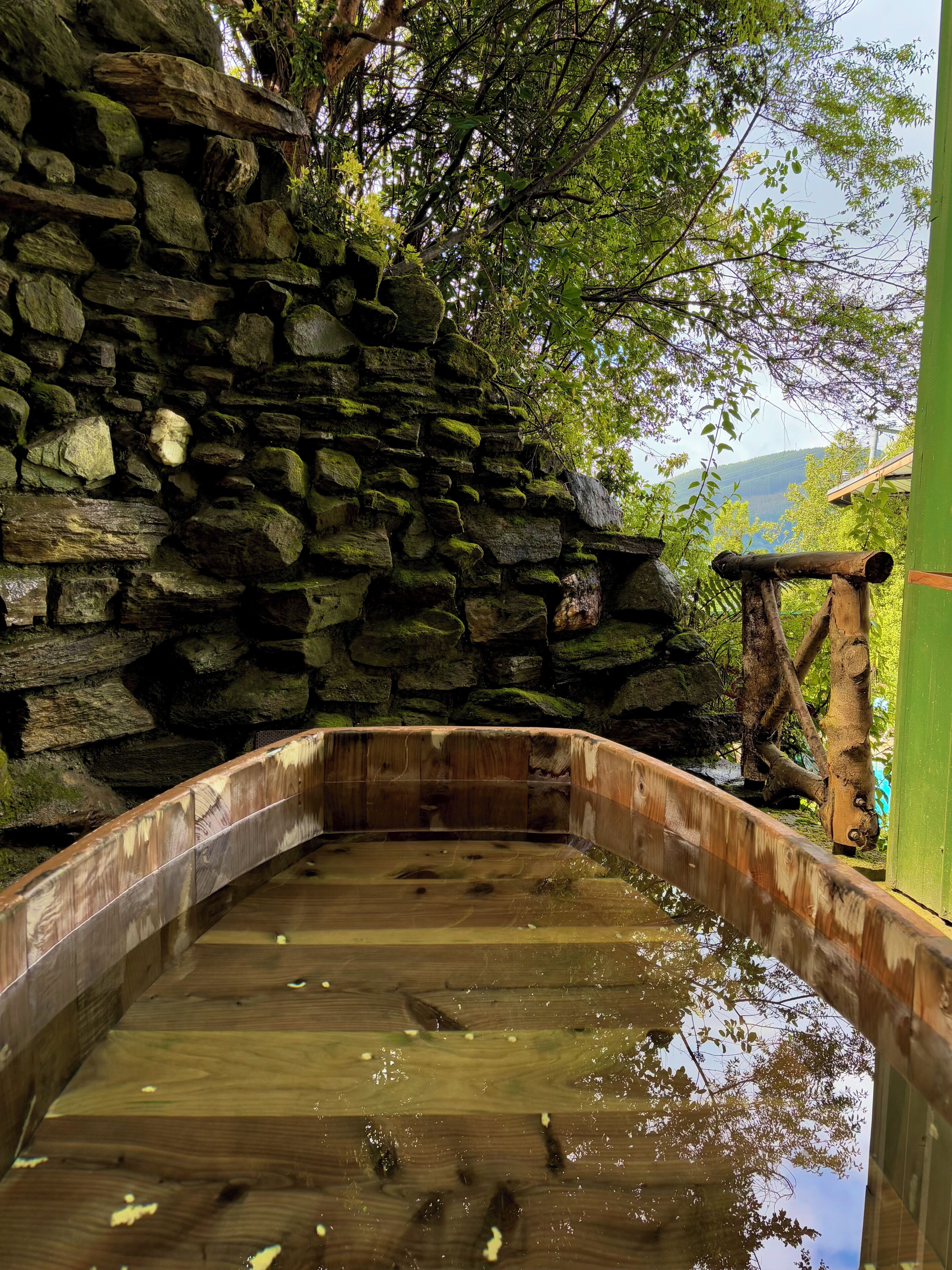 A stone wall with a wooden bridge over a reflective water surface.