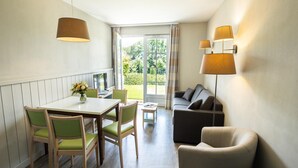 Una habitación compacta con una mesa de comedor, sillas, un sofá y una lámpara.