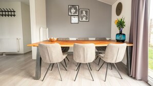 Ein moderner Essbereich mit einem Holztisch, vier Stühlen und einer Vase mit Blumen.