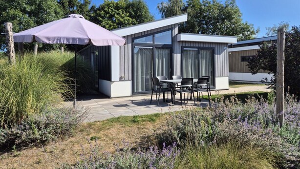 Ein modernes Haus mit Terrasse, Tisch und Stühlen.