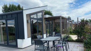 Eine moderne Außenpatio mit Esstisch und Stühlen, einer Glasveranda und einer Holz-Pergola.