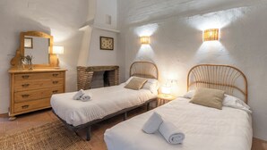 A bedroom with two beds, a dresser, a mirror, and a wall-mounted lamp. - MOLÍ DE CAN BURJATS (Mont-ras)