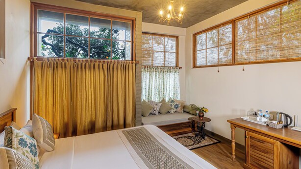 A room with a bed, a sofa, a table with a kettle, and a window with curtains. - Villa Nugaliyadda (CP)