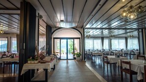 A spacious restaurant with a high ceiling, multiple tables, and a view of the outdoors. - Hotel Issa - Double Room Sea View 5 (Vis)
