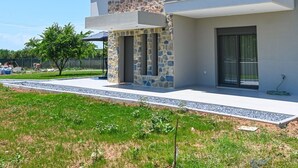 A two-story house with a stone facade, a balcony with glass railings, and a clear sky. - Estelle luxury living Premium Apartment in Paralia Dionisiou (102) (Paralia Dionisiou)