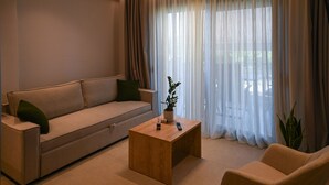 A living room with a sofa, a coffee table, and a chair. - Estelle luxury living Premium Apartment in Paralia Dionisiou (102) (Paralia Dionisiou)