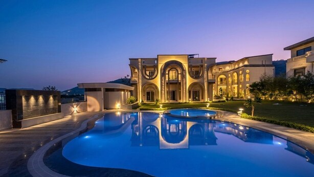 Uma área de piscina luxuosa, com um edifício grande e bem iluminado ao fundo.