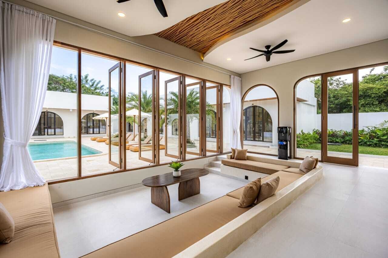 A spacious living area with a pool view, large windows, and a ceiling fan.