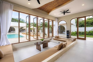A spacious living area with a pool view, large windows, and a ceiling fan.