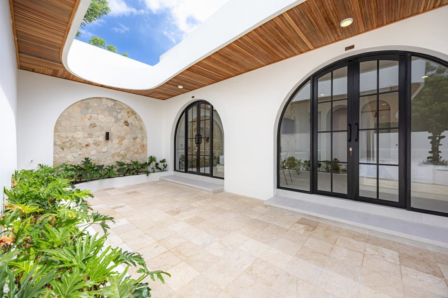 A spacious patio with stone walls, large arched windows, and a wooden ceiling.