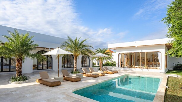 A modern outdoor pool area with lounge chairs and palm trees.