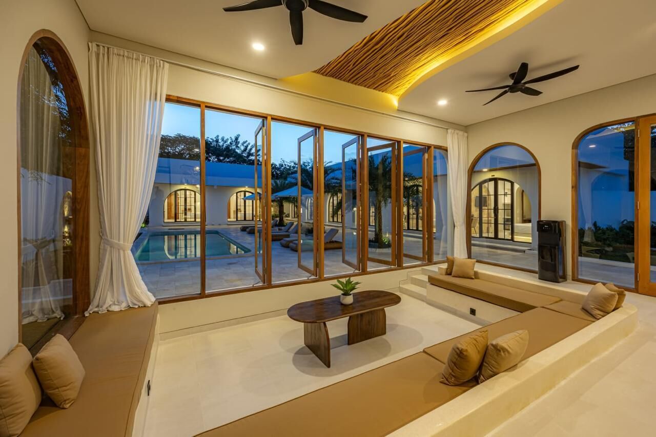 Ein großzügiger Wohnbereich mit großem Fenster und Deckenventilator, mit Blick auf einen Pool.