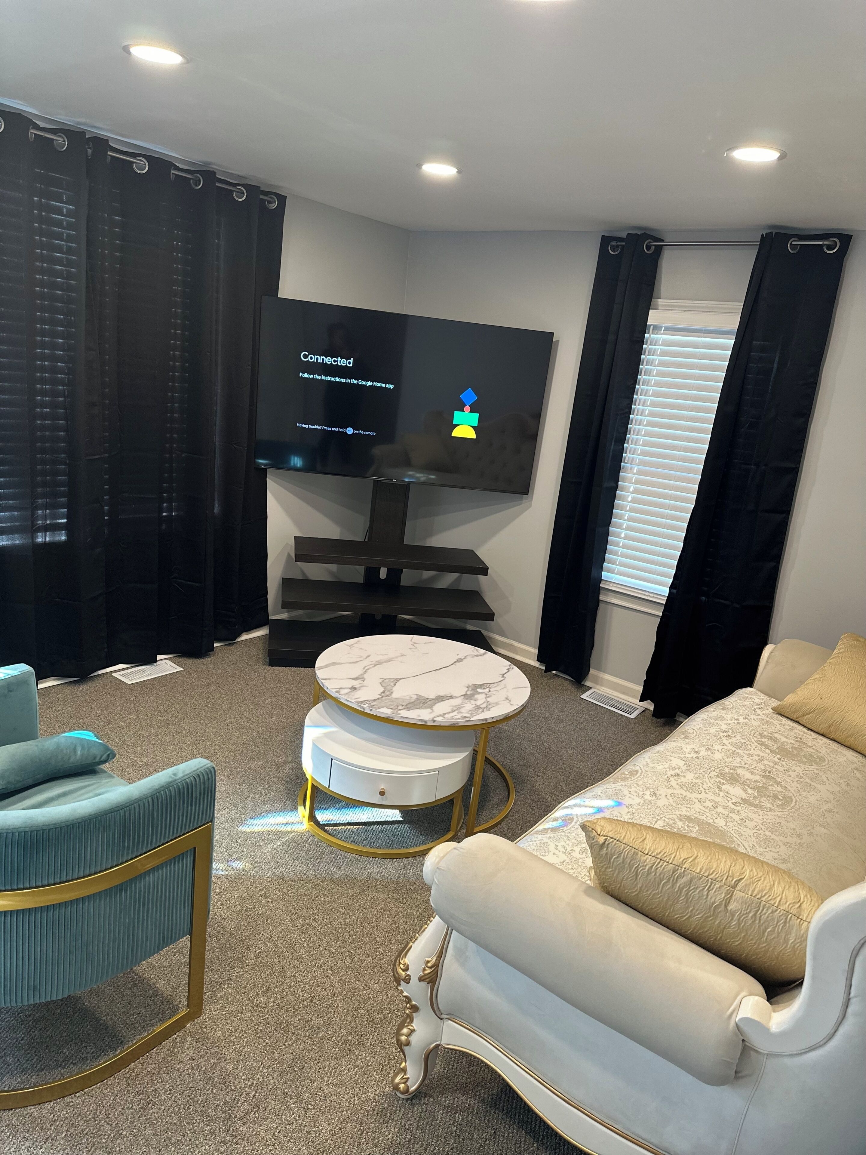 A modern living room with a flat-screen TV, a round marble coffee table, a sofa, and a chair.