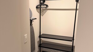 A black metal shelf unit with three levels, a white wall, and a patterned rug.
