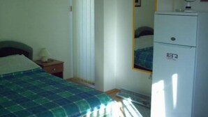 Ein Schlafzimmer mit Bett, Nachttisch, Spiegel und Kühlschrank.