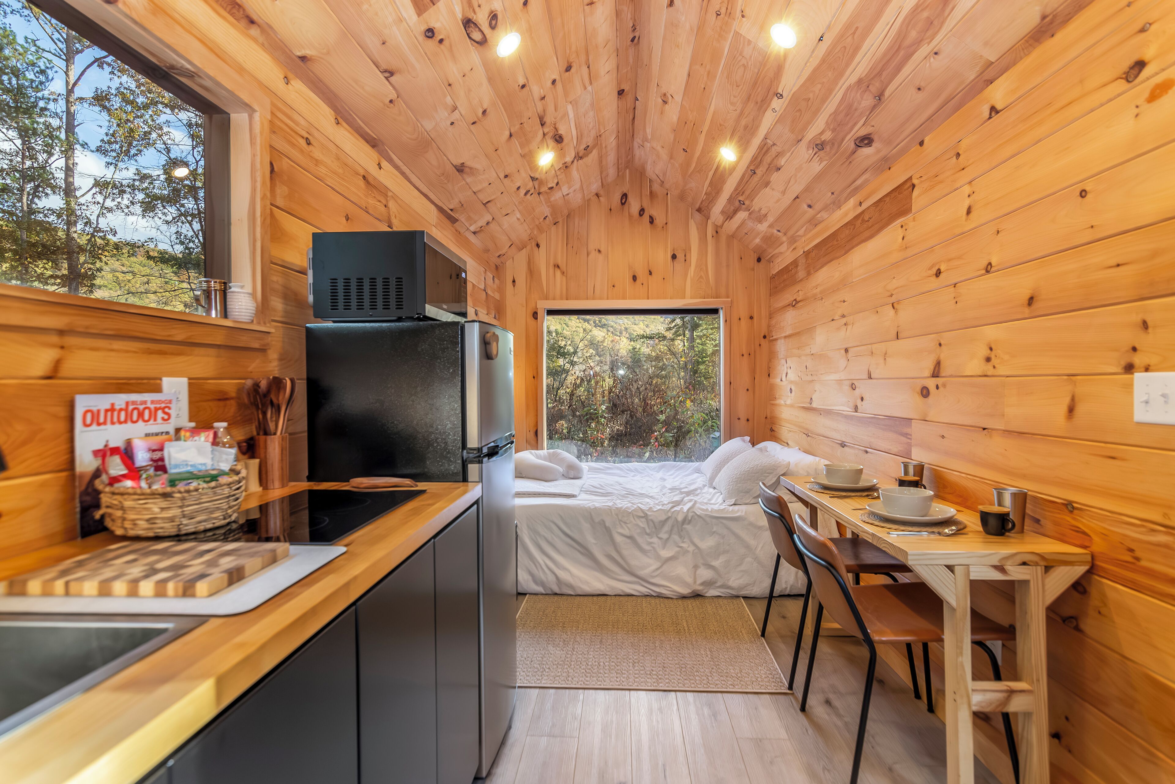 A compact cabin with a kitchenette, a bed, and a dining area.
