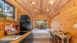 A compact cabin with a kitchenette, a bed, and a dining area.