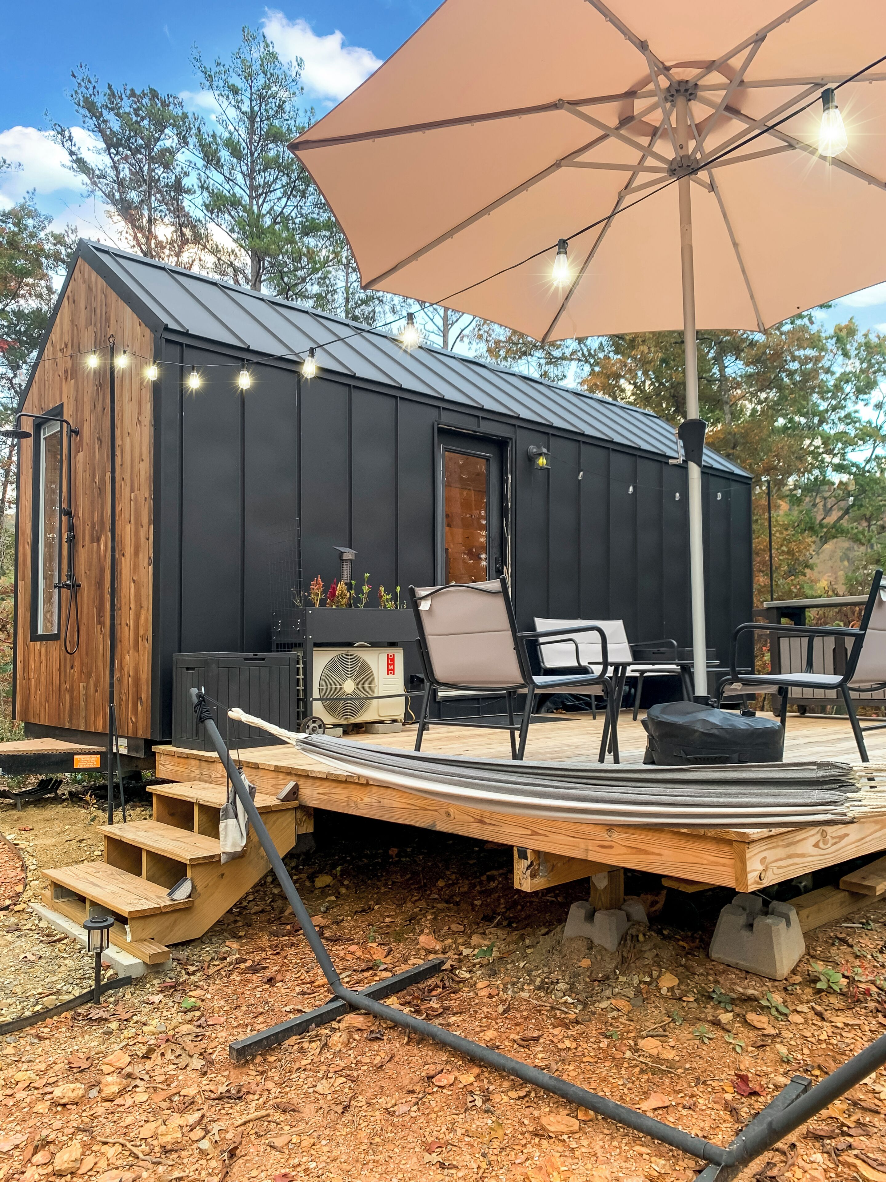 A small cabin with a deck, outdoor seating, and a fan.
