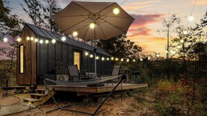 A small cabin with a deck, outdoor seating, and string lights.