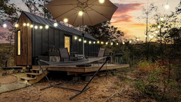 A small cabin with a deck, outdoor seating, and string lights.