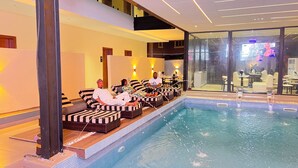 Un espace aménagé au bord de la piscine, avec des chaises longues, une piscine et une vue sur l’intérieur.