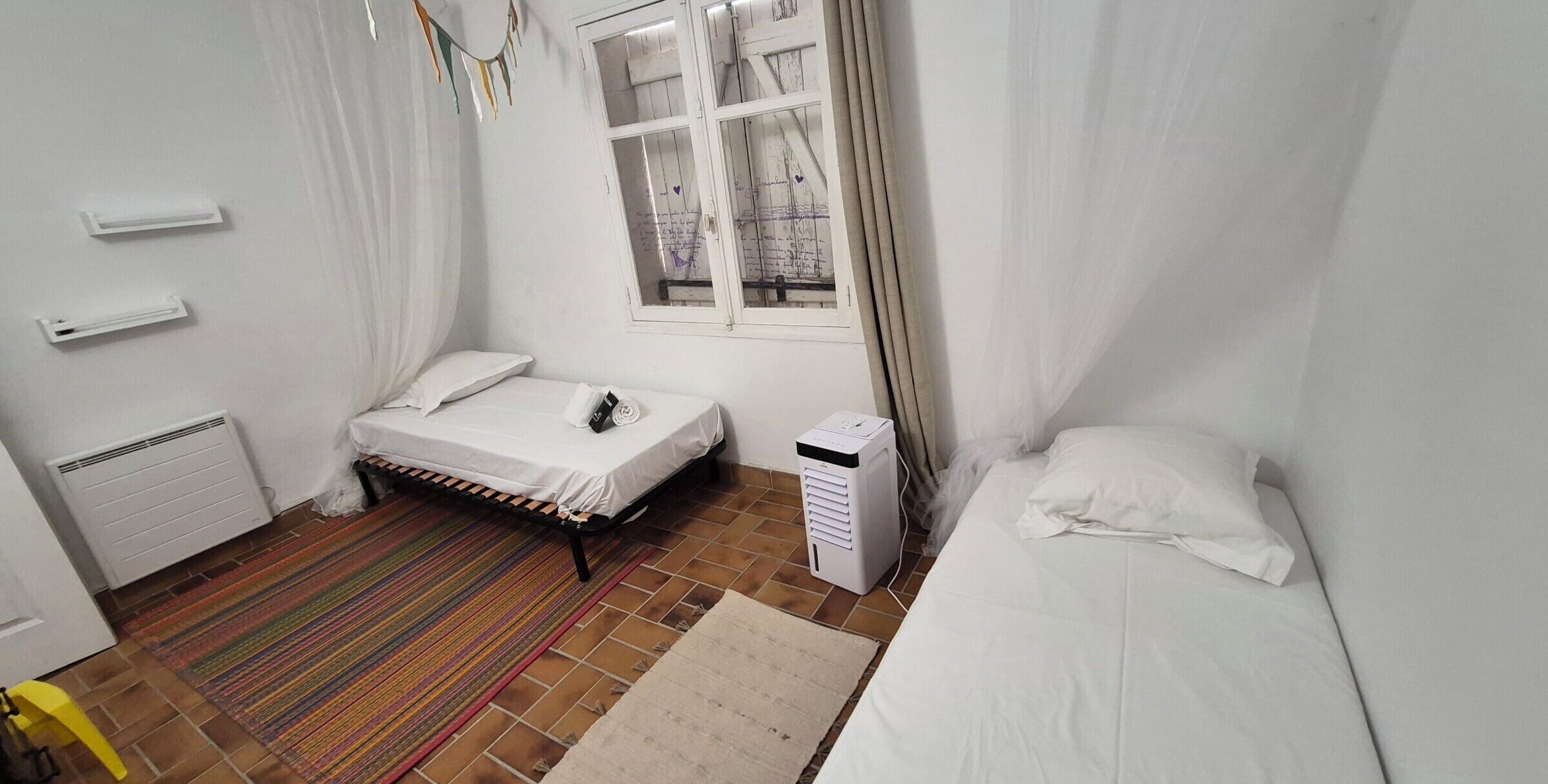 Une chambre à coucher avec un lit, un radiateur, une fenêtre et un chauffage d’appoint.